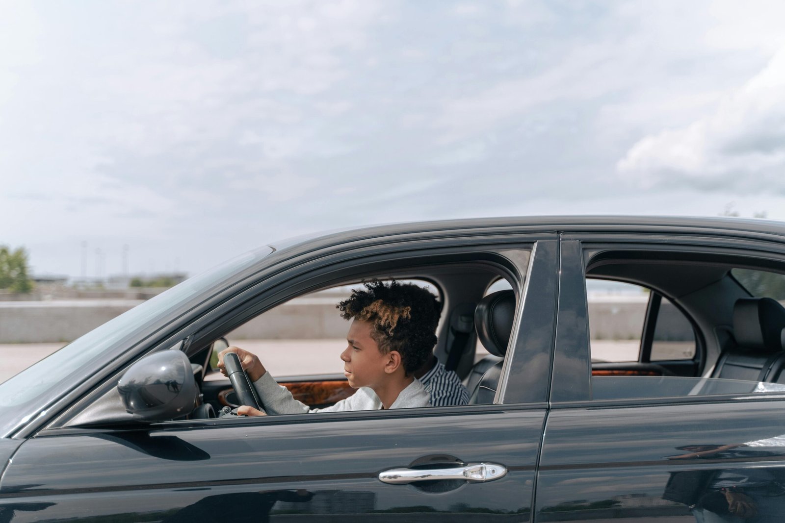 Side view of a young male teenager focused on driving a car